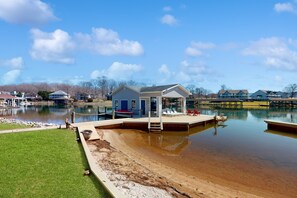 Una propiedad frente al lago con un muelle, una casa pequeña y una zona para nadar.
