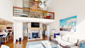 A spacious living area with a fireplace, a dining area, and a loft with a balcony. - Sail Away - Waterfront Home With Private Beach on the Lake, hot Tub, & Dock (Huddleston)