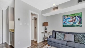 A living room with a grey sofa, a patterned rug, and a painting on the wall. - Reel Simple - Waterfront Striper's Landing Condo With Views, Pool & Boat Launch - Near Dining (Moneta)