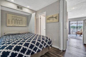 A bedroom with a bed, a door leading to a balcony, and a fish illustration on the wall.