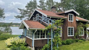 A wooden house with a balcony, a staircase, and a view of a lake. - Charming and attractive house! (Prässebo)