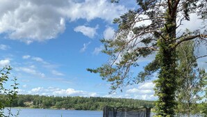 A grassy area with a trampoline and a lake in the background. - Charming and attractive house! (Prässebo)