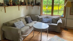 A living room with a sofa, a round table, and a window with a view of greenery. - Charming and attractive house! (Prässebo)