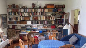 A cozy living room with a wooden floor, a blue checkered table, wooden chairs, a blue sofa, and a bookshelf filled with books and decorative items. - Charming and attractive house! (Prässebo)
