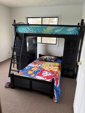 A bunk bed with a colorful bedspread, a ladder, and a window with a view of trees. - Lake access, family friendly 4-bedroom house with AC in outskirts of Rexburg (Rexburg)