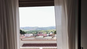 Quarto com vista para uma varanda com azulejos e guarda-corrimão branco.