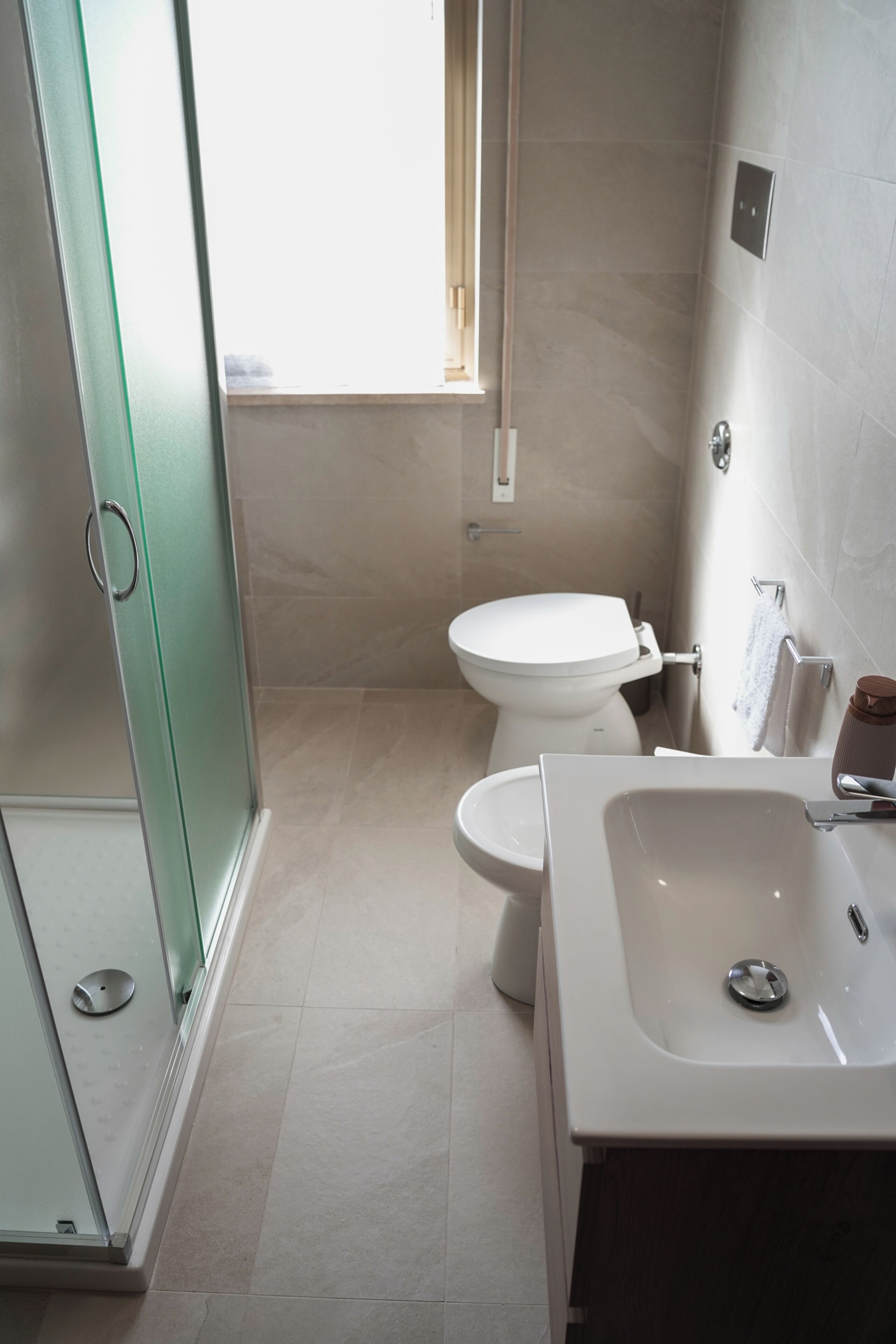 Een badkamer met een douchecabine van glas, een toilet en een wastafel.