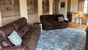 A living room with a brown leather sofa, a patterned rug, and a ceiling fan. - Family friendly house in the center of Walden, CO (Walden)