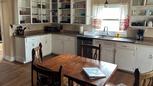 A kitchen with white cabinets, a wooden dining table, and a window with curtains. - Family friendly house in the center of Walden, CO (Walden)