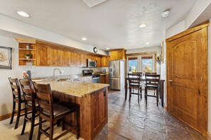 A kitchen with wooden cabinets, granite countertops, stainless steel appliances, and a stone tile floor. - Ski/Lake condo near Basin/Powder/Nordic/Pineview (Eden)