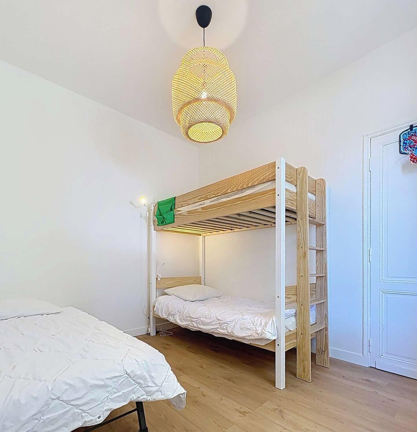 Habitación con literas, una lámpara colgante y una puerta decorada con colores.