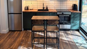 Een moderne keuken met houten plafond, roestvrijstalen apparatuur en een houten eettafel.