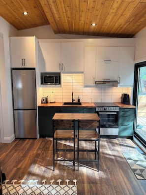 Eine moderne Küche mit Holzboden, Edelstahlgeräten und einem Holzespeisetisch.