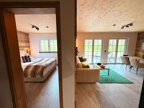 Una camera da letto con un letto, una finestra e un comodino. La stanza ha un soffitto in legno e vista sull'esterno dalla finestra.