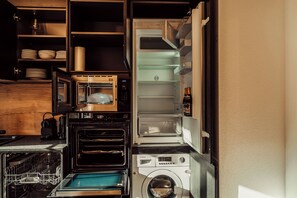 A compact kitchen with a built-in oven, a dishwasher, and a washing machine. - Forestum - Black Forest Luxury Apartments - Apartment Gams with sauna (Sankt Blasien)