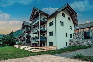A multi-story building with balconies, a stone wall, and a wooden fence. - Forestum - Black Forest Luxury Apartments - Apartment Gams with sauna (Sankt Blasien)
