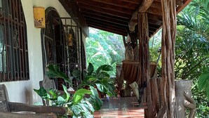 A covered outdoor area with tiled flooring, wooden furniture, and potted plants. - 4-bedroom farmhouse in gorgeous Nuevo Colón with cool AC breeze (Nuevo Colón)