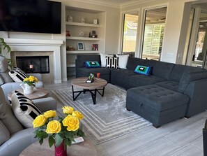 A modern living room with a sectional sofa, a coffee table, and a fireplace.