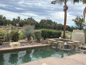 A pool area with a water feature, surrounded by palm trees and a landscaped garden.