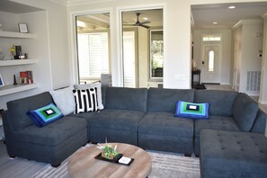 A modern living room with a sectional sofa, a coffee table, and a bookshelf.