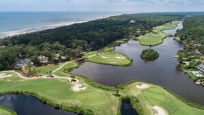 Een golfbaan met diverse waterhindernissen, een brug en een strand op de achtergrond.