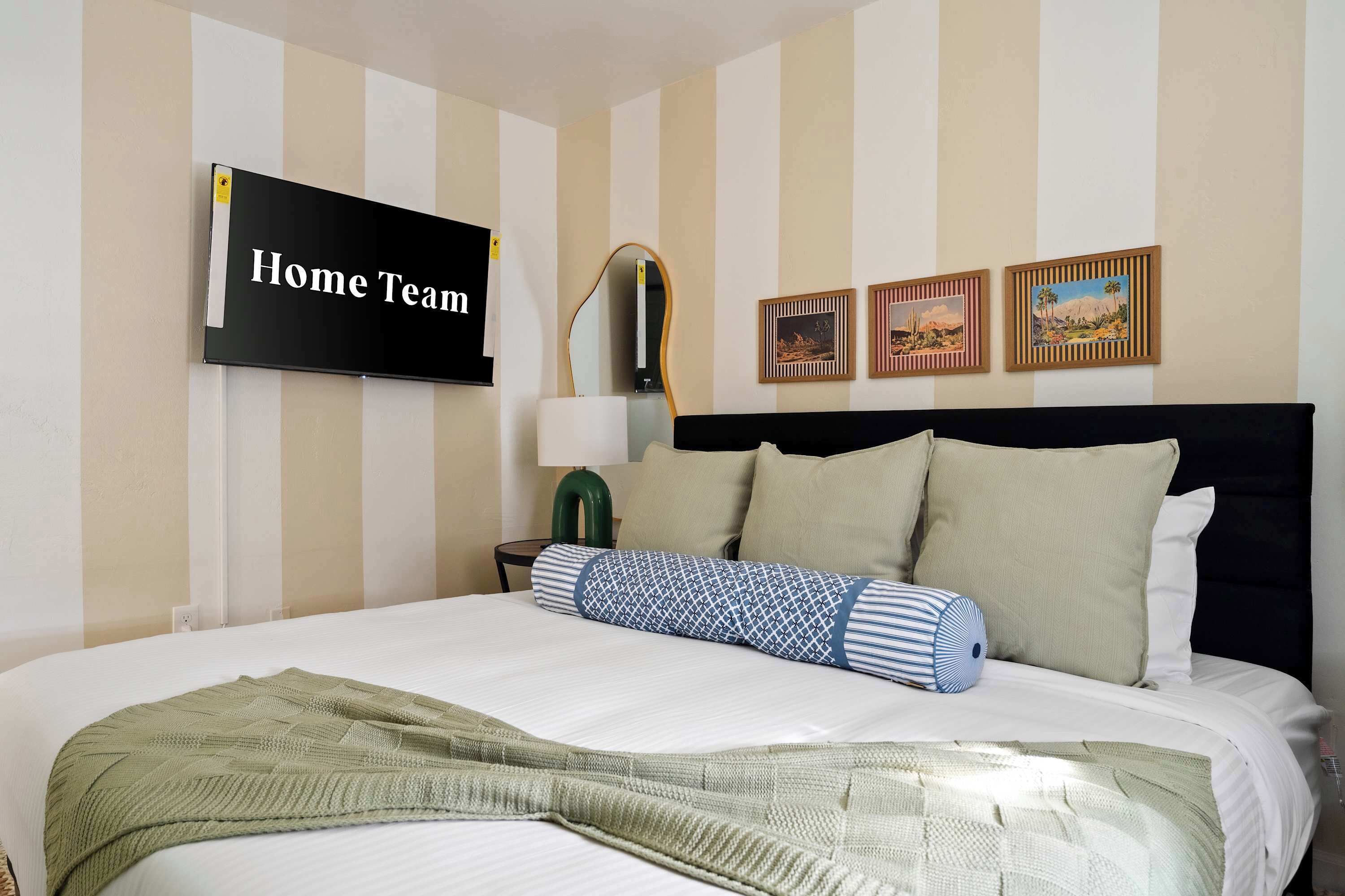 Une chambre d’hôtel avec un lit, une télévision, une lampe et trois tableaux encadrés accrochés au mur.