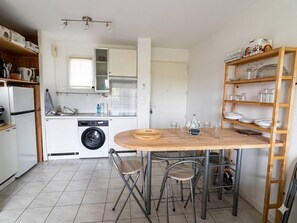 Eine kleine Küche mit Waschmaschine, einem Esstisch mit Stühlen und einer Ablage für Geschirr.