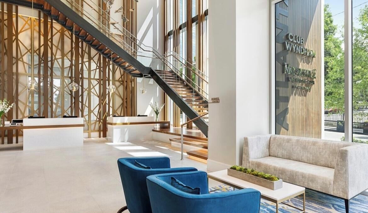 Un hall d’entrée moderne avec un escalier, un espace salon et un comptoir d’accueil.