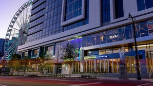 A modern building with a large Ferris wheel in the background, a restaurant named 'Margaritaville Store' on the ground floor, and a sign for 'Party in Paradise' advertising events and groups. - Downtown Atlanta Wyndham Studio Suite - World Cup Stay Near Stadium (Atlanta)