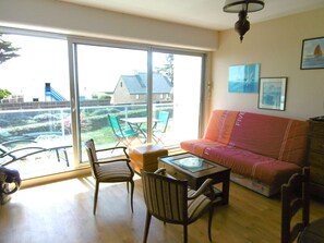 Ein Wohnzimmer mit einer Couch, Sesseln, einem Tisch und einer großen Schiebeglasdoor zur Garten.