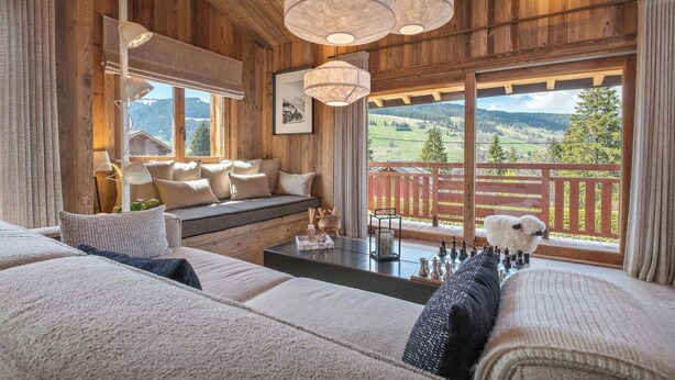 Una habitación acogedora con techo de madera, un sofá con cojines, una mesa con piezas de ajedrez y vistas al exterior.