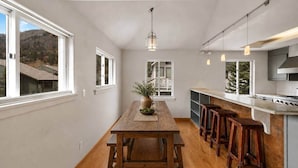 A modern kitchen with a wooden table, bar stools, and a view of the outdoors. - Sky Loft: Steps to skiing w/ hot tub! (Telluride)