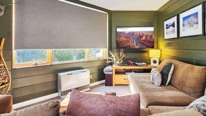 Un salon avec un canapé, un téléviseur, un radiateur et des tableaux encadrés accrochés au mur.