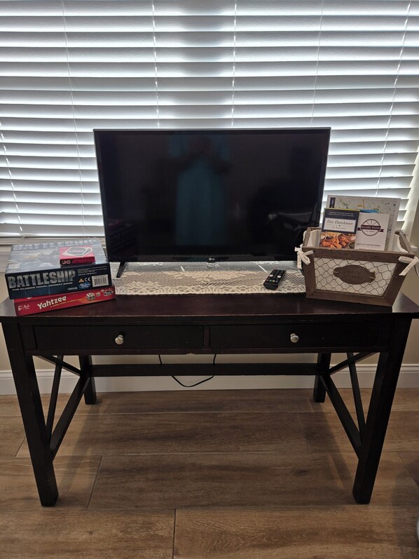 Una mesa de madera oscura con un televisor de pantalla plana, un juego de mesa y un libro.