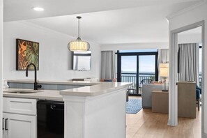 A modern hotel room with a kitchen area, a dining space, and a balcony with a view. - Stunning 3bedroom ocean front at Ocean Reef (Myrtle Beach)