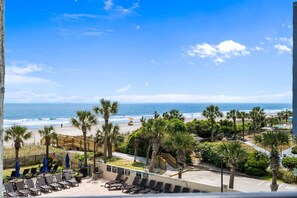 A beach view with lounge chairs, palm trees, and a wooden deck. - Stunning 3bedroom ocean front at Ocean Reef (Myrtle Beach)