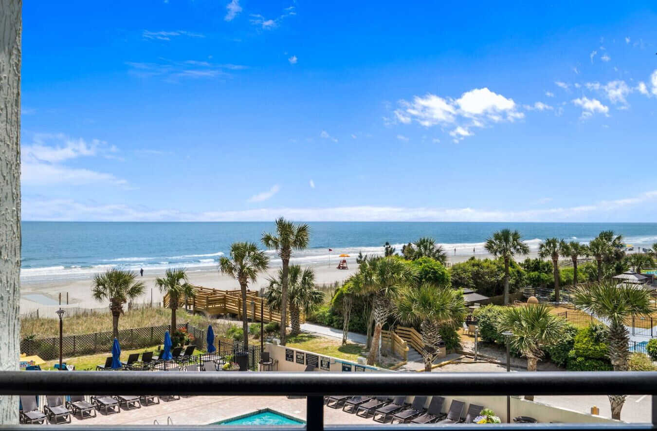 Blick auf ein Schwimmbecken mit Strand und Palmen.