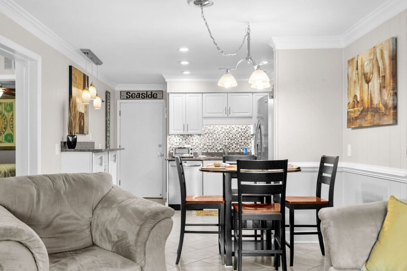 Una cocina moderna con armarios blancos, un comedor con mesa y sillas de madera, y un cartel que dice 'Seaside'.