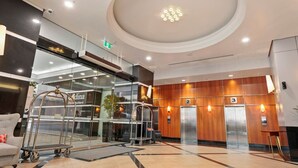 A modern lobby with a glass entrance, elevators, and a reception desk. - Cosy Cityview Modern Studio | Pool - Gym - Aircon (Auckland CBD)