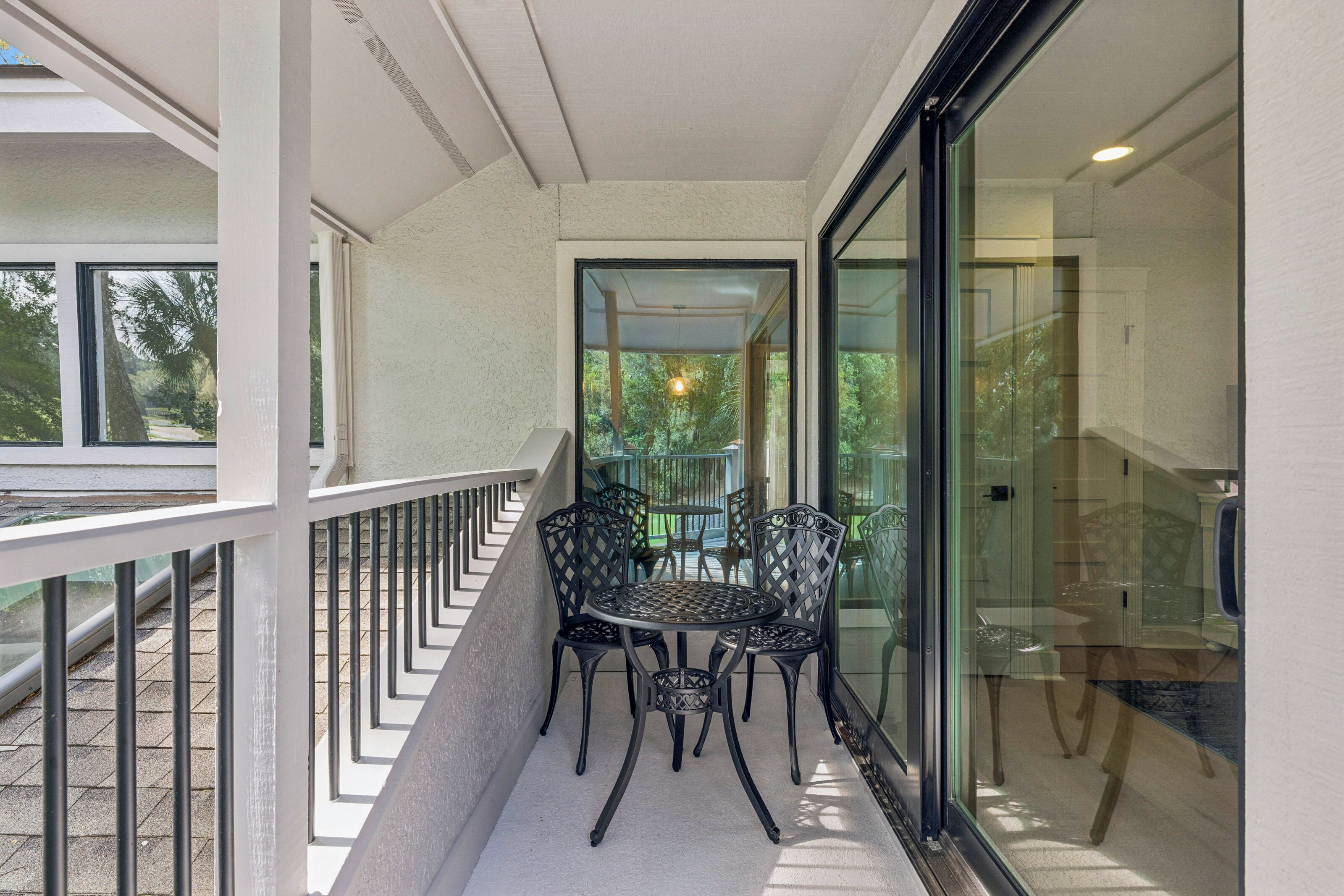 A balcony with a glass door, a round table, and four chairs.