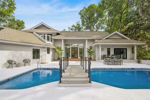 Ein Haus mit Pool, einer überdachten Terrasse und einem Eingang.