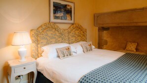 Une chambre à coucher avec un lit, une table de chevet avec une lampe, un tableau encadré au mur et une couvre-lit à motifs.