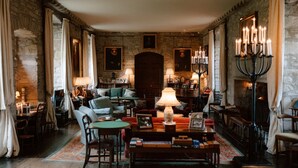 Une pièce chaleureuse avec une cheminée, un canapé, une table avec des livres et une lampe.