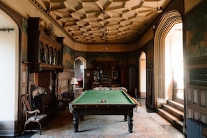 A billiards room with a pool table, wooden chairs, and a high ceiling with a geometric pattern. - Historic Castle in Norfolk (King's Lynn)