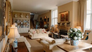 A spacious living room with a sofa set, a fireplace, and a bookshelf.