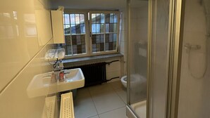 Een badkamer met douche, toilet en wastafel.