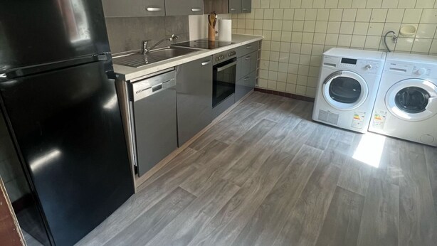 Een keuken met een koelkast, vaatwasser, oven en wasmachines.