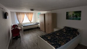 Een kamer met een bed, een bureau, een stoel, een kledingkast en een raam met gordijnen.