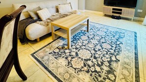 Ein Wohnzimmer mit einer Couch, einem Couchtisch, einem Fernseher und einem gemusterten Teppich.