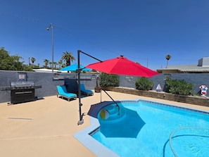 A swimming pool with a red umbrella, lounge chairs, and a barbecue grill. - Private Studio - 10 minutes from LV Strip, airport, and Convention Center (Las Vegas)